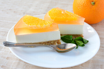 two slices of Orange Jelly Cheesecake with teaspoon on the saucer