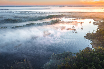 Drone panorama on tiny isles in lake in colorful sunrise colors. Top down view on swamp with isle. Sustainable ecosystem of wetlands.