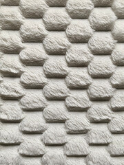 White fluffy textile texture with a repetitive raised pattern, creating a plush and cozy fabric...