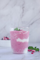 a glass of mixed berry yogurt smoothie on marble table background. 