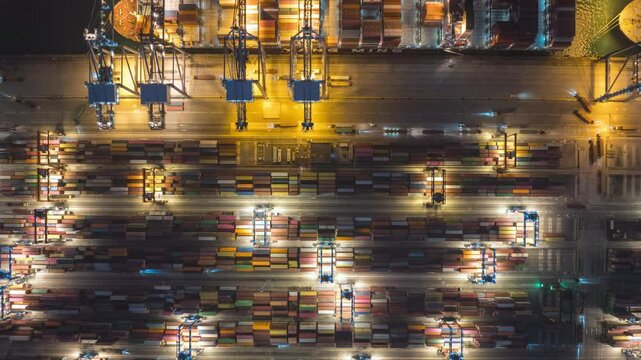 Aerial hyperlapse timelapse of cargo ship loading and unloading with crane at night. Industrial shipyard, containers, car traffic, freight transportation, International business logistics industry. 