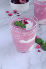 a glass of mixed berry yogurt smoothie on marble table background. 