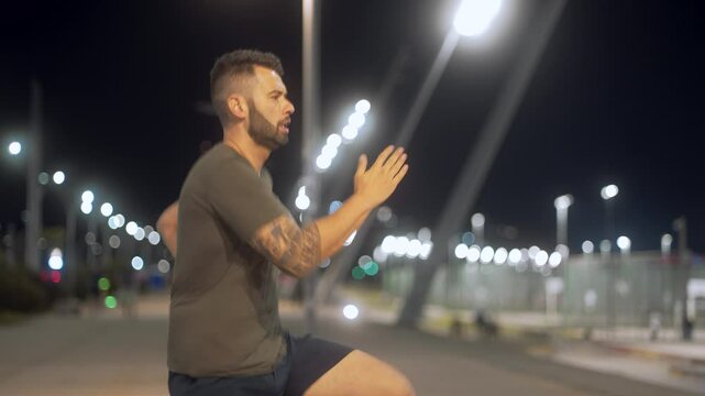 Focused athlete practicing quick leg skipping during nighttime workout. Energetic man in sportswear performing dynamic exercises in an illuminated urban setting.