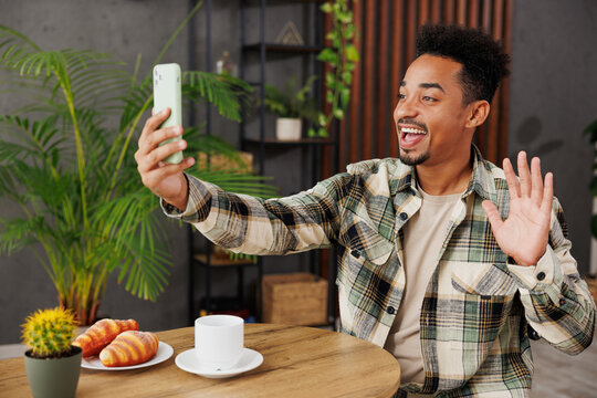 Young fun man wear grey casual clothes doing selfie shot on mobile cell phone post photo on social network sitting alone at table in coffee shop cafe relax rest in restaurant during free time indoors.
