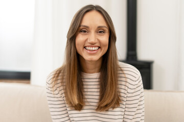 Young latin woman smiling and relaxing on sofa at home