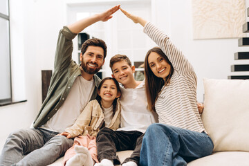 Happy family smiling and making house roof gesture with hands