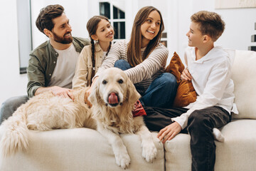 Happy family petting golden retriever dog on sofa at home