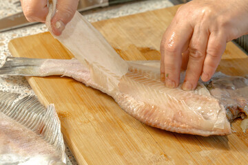 Chef removes the skin from a fresh flounder fish for further cooking