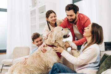 Happy family playing with golden retriever dog at home