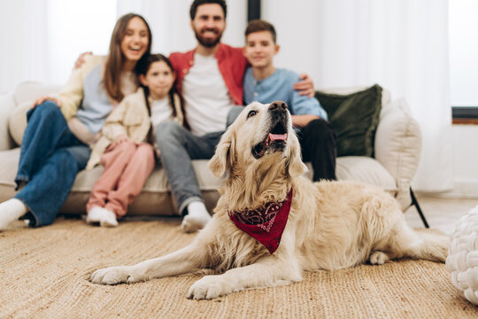 Happy family relaxing on sofa with golden retriever dog