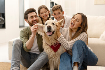 Happy family playing with golden retriever dog at home