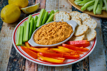 roasted red pepper hummus with vegetables and crackers, served in a white dish