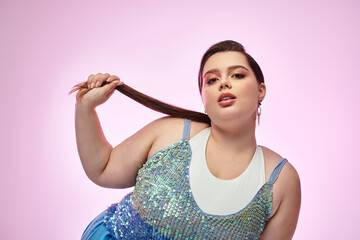 Confidence shines as a stunning young plus size woman poses gracefully against a pink backdrop