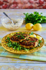 crispy fried crab cake served with fresh lemon, parsley, and tartar sauce on a yellow plate