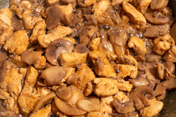 A close-up view of cooked chicken pieces and sliced mushrooms.
