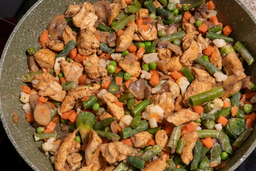 A close-up view of a pan filled with a variety of frozen mixed vegetables, including green beans, peas, carrots, cauliflower, and Brussels sprouts.