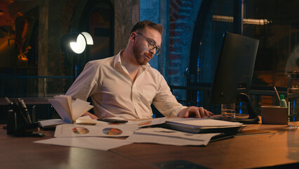 Caucasian man business guy businessman male workaholic in dark night office overworked overtime tired exhausted yawning low energy late time need sleep deadline working computer yawn health insomnia