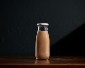 Cold brew Coffee latte with nut milk glass bottle on wooden table with dark background