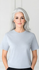 Portrait of a mature smiling woman, with silver hair, wearing a gray T-shirt against white backdrop