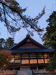 Obraz premium serene view of traditional Japanese temple at dusk, surrounded by lush greenery and clear sky. architectural details and natural elements create peaceful atmosphere