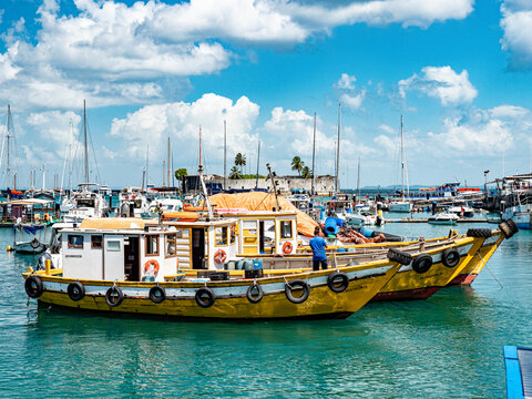 Colorful fishing boats moored side by side in the Port of Salvador, with Forte de Sao Marcelo in the background