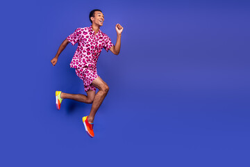 Fototapeta premium Energetic young man in colorful leopard outfit posing against a vibrant purple backdrop showcasing fun and charisma