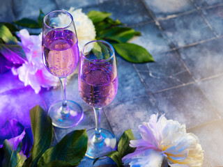 Champagne glasses on a blue table and white peonies. Copy space