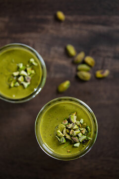 Pistacio Butter in glass jar with nuts on wooden table dark background