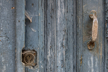 part of an old door with a rusty lock and handle covered in cobwebs