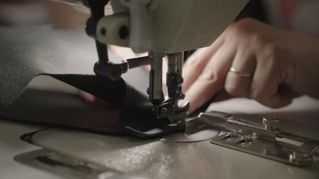 experienced worker works sewing machine. sew leather goods. hands close up. workshop business concept. female hands sew clothes sewing machine. professional seamstress workshop. clothing production