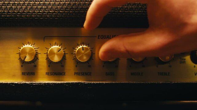 Close-up of plugging a jack into a guitar amplifier and turning up the volume knob, live concert show, playing music on guitar tube amplifier.
