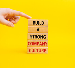 Naklejka premium Company culture symbol. Wooden blocks with words Build a strong company culture. Businessman hand. Beautiful yellow background. Business and Company culture concept. Copy space.