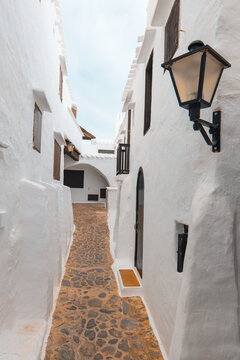 The charming town of Binibeca on Menorca. Narrow streets and white walls of houses with wooden elements, Mediterranean architecture, wonderful Spain.