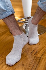 Men's legs in gray short socks on the background of the interior.
