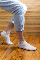 Men's legs in gray short socks on the background of the interior.