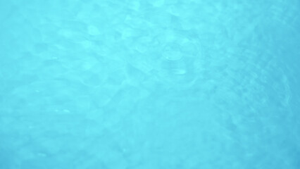 Background with clear blue water. Top view, copy location, text location. Blurred background, transparent water surface with splashes and wave texture with ripples