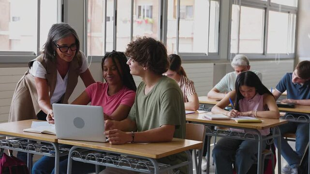 High school female teacher helping diverse young students in classroom. Education lifestyle concept