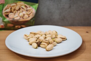 Pistachios on a white plate with a blurred background