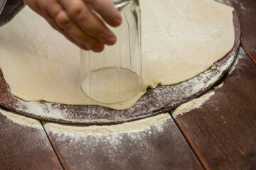 A woman's hand makes dough blanks on a wooden table
