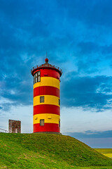 Der gelb-rote Leuchtturm vor dramatischem Himmel