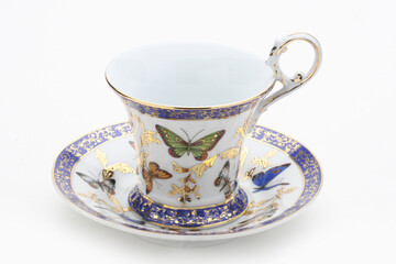 Fine porcelain teacup and saucer featuring a colorful butterfly design, accented with gold and blue details, set against a clean white backdrop