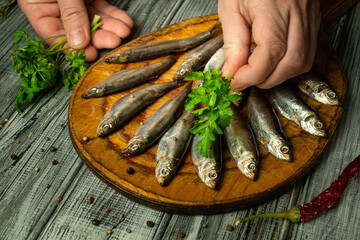 Hands delicately arrange fresh fish on a wooden platter, adding vibrant herbs or parsley. The...