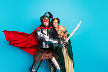 Naklejka premium Playful Couple in Medieval Knight and Princess Costumes Against a Vibrant Pink Background