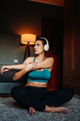 Young caucasian woman doing yoga or stretching while listening to music