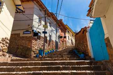 Calle empedrada en barrio hist&oacute;rico con coloridas fachadas coloniales bajo cielo azul. Encanto urbano y arquitectura tradicional.