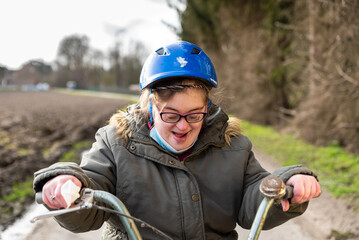 Happy 39 yo woman with the Down Syndrome sitting on her tricycle outdoors, Tienen, Flanders, Belgium