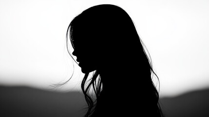 A woman stands in profile, her silhouette clearly defined against a softly illuminated background. The flowing hair creates a graceful outline as daylight fades