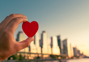 hand holding heart on New York city background showing love charity support compassion, helping friend in need, Valentine's Day concept	