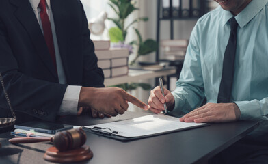 Legal Counsel: A professional lawyer points to a legal document as his client signs, symbolizing...