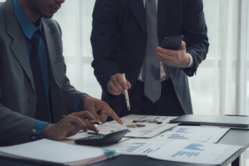 Strategic Collaboration: Two focused businessmen meticulously review financial charts and data,...